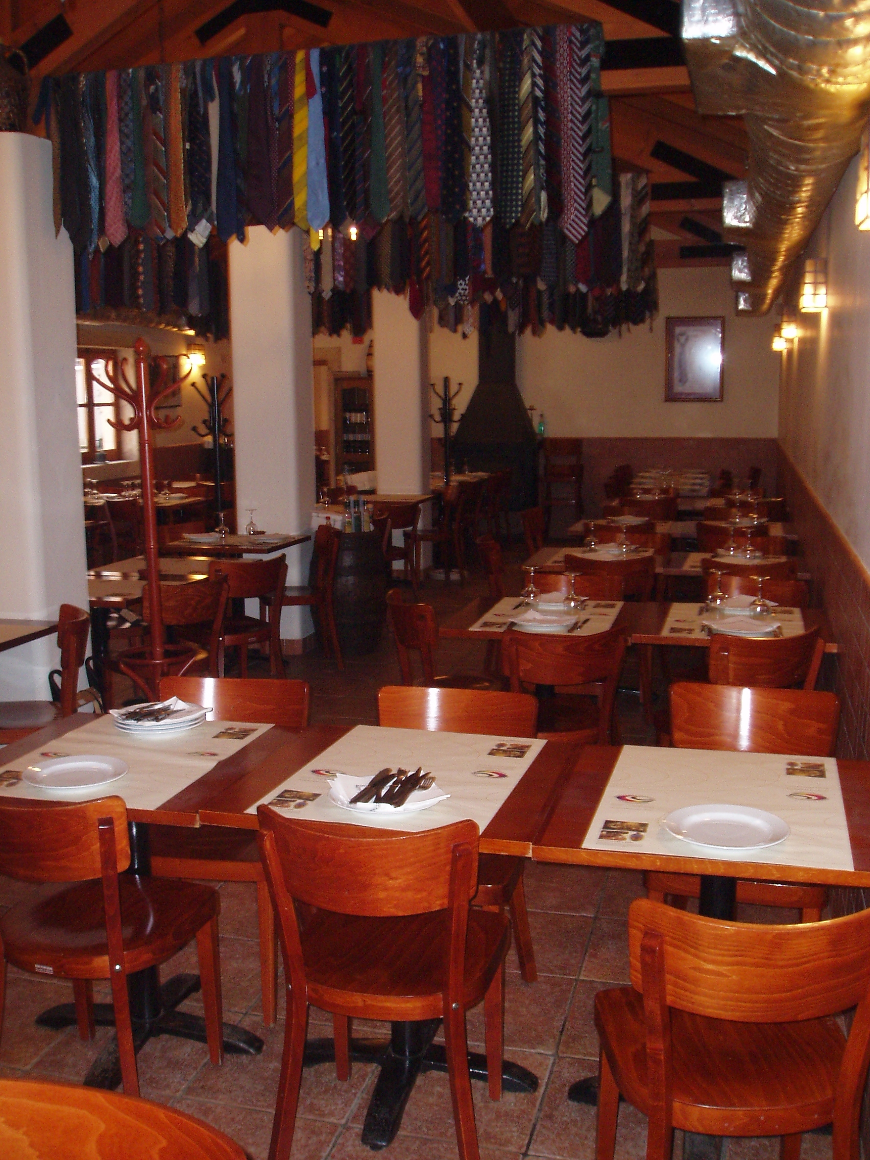 Sala da Adega das Gravatas, com mesas de madeira e gravatas penduradas
